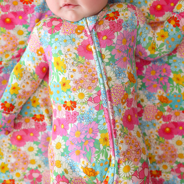 Baby in a colorful floral one piece against a matching floral background