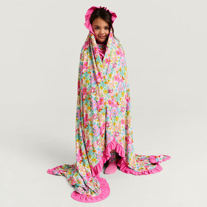 Child wrapped in a colorful floral blanket on a plain background