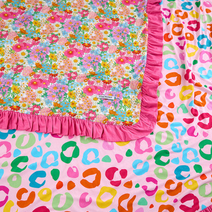 Two colorful baby blankets with floral and leopard print patterns on a pink background.