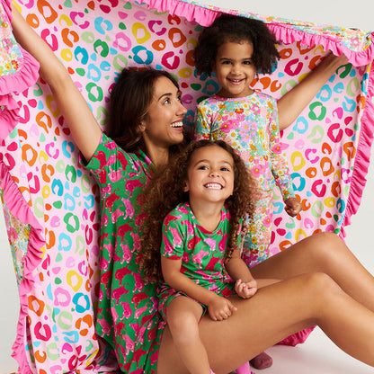 Woman and two children in matching colorful pajamas sitting inside a colorful blanket