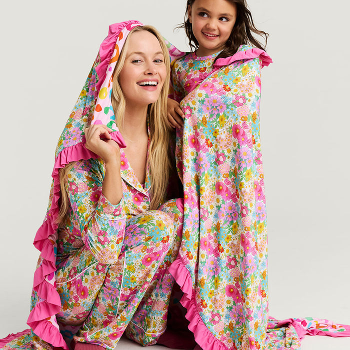 Woman and child wearing colorful floral blanket on a white background