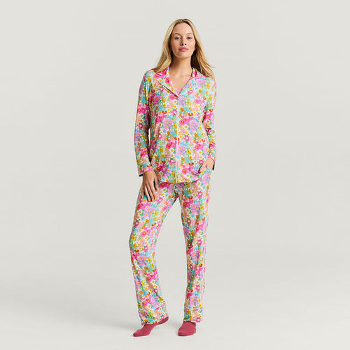 Woman wearing a colorful floral pajama set on a plain background