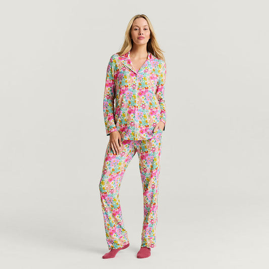 Woman wearing a colorful floral pajama set on a plain background