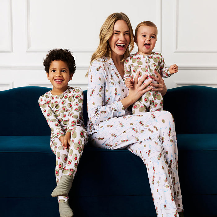 Woman and two children in matching pajamas sitting on a blue couch.