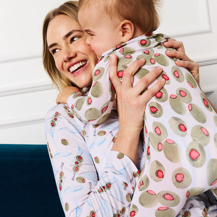 Woman holding a baby in a olive patterned one piece
