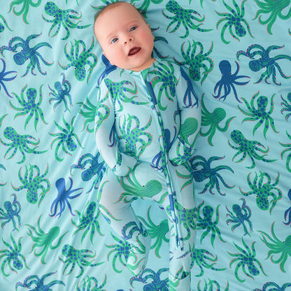Baby lying on a blanket with octopus pattern wearing a bamboo viscose one piece