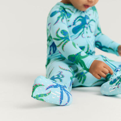 Child wearing a blue octopus patterned onesie on a light gray background