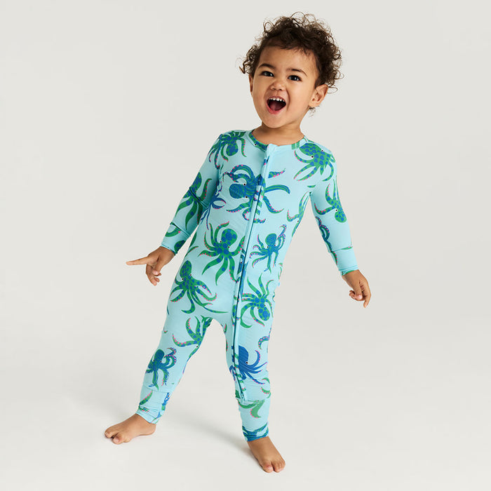 Child wearing a blue onesie with octopus pattern on a white background
