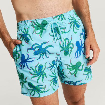 Blue swim shorts with octopus pattern worn by a person on a plain background