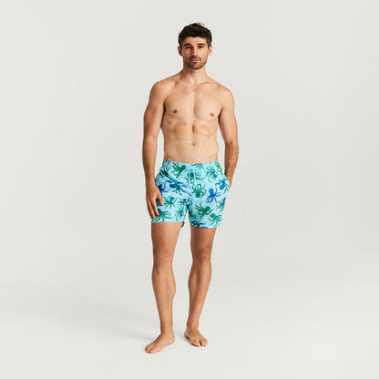 Man wearing a patterned swim trunk on a plain background