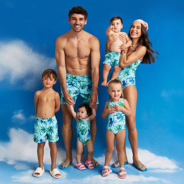 Family of six wearing matching blue swimwear  against a blue sky background