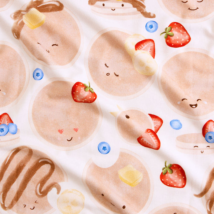 Pattern of cartoon-like cookies with faces, strawberries, and blueberries on a white background.