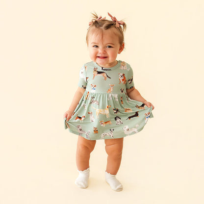 Child wearing a dress with dog pattern on a beige background