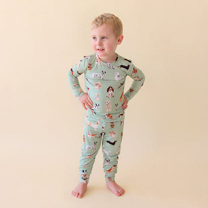 Child wearing a green pajama set with dog pattern on a beige background