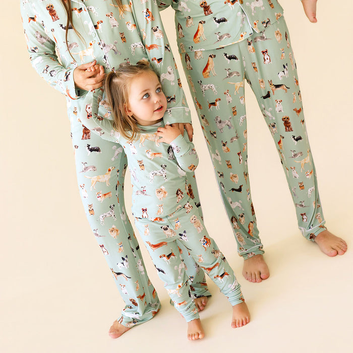 Two adults and child wearing matching pajamas with dog pattern on a beige background