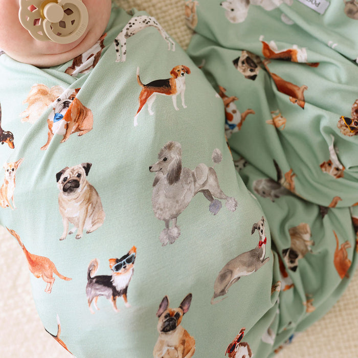 Light green fabric with dog pattern, held by a baby wearing a green outfit.