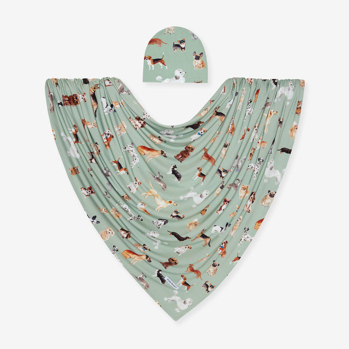 Baby swaddle and beanie set with dog pattern on a light green background