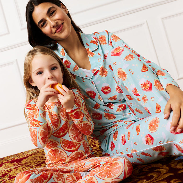 Woman and child wearing matching pajamas with orange pattern on a white background