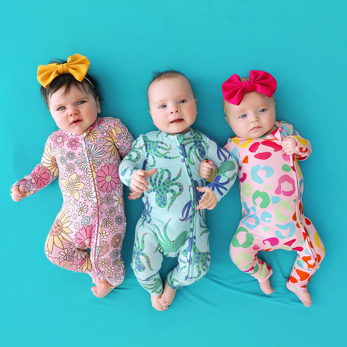 Three babies wearing colorful outfits with patterns on a blue background