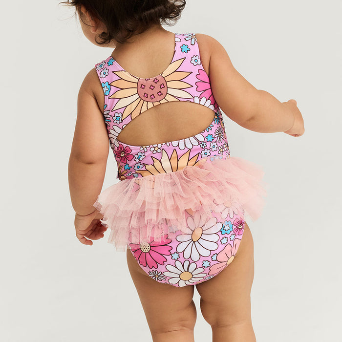Child wearing a floral swimsuit with a tutu on a light gray background