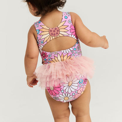 Child wearing a floral swimsuit with a tutu on a light gray background