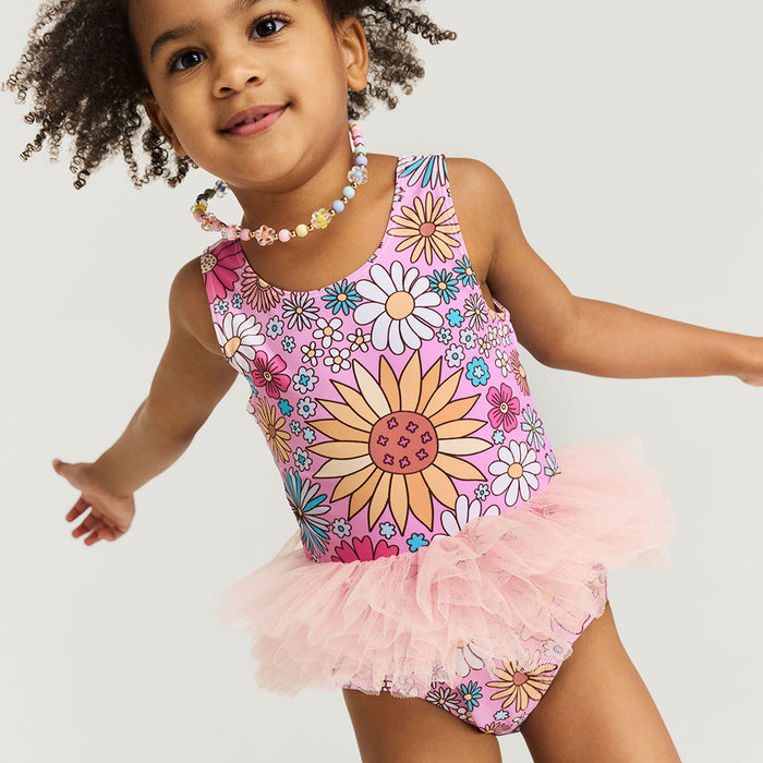 Child wearing a floral swimsuit with a tutu on a plain background