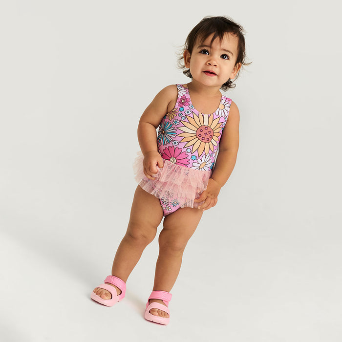 Child wearing a colorful floral swimsuit with a tutu on a white background