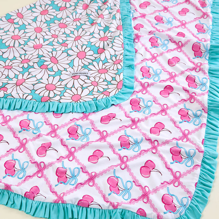 Reversible baby blanket with floral and bow patterns on a white background.