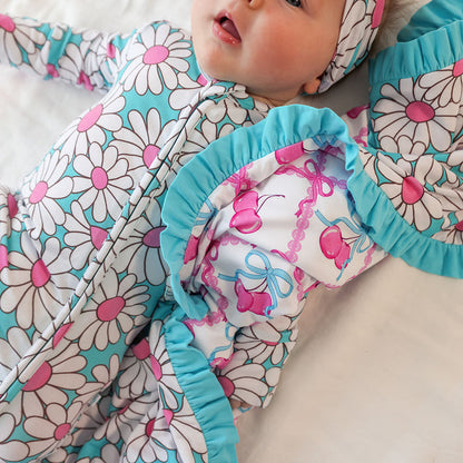 Baby doll wrapped in a floral-patterned blanket with blue trim on a light background