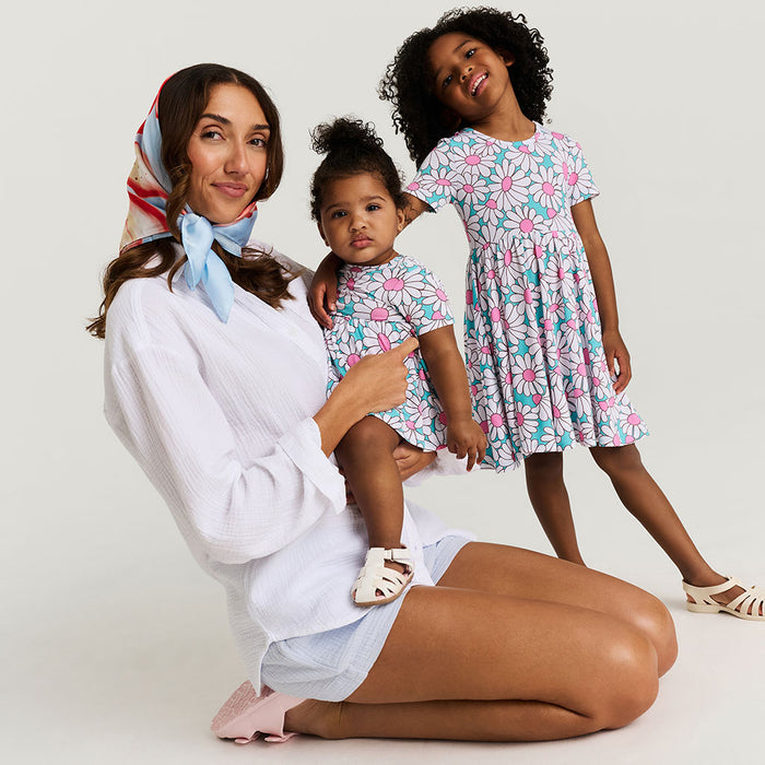 Woman with two young girls wearing matching floral dresses on a white background