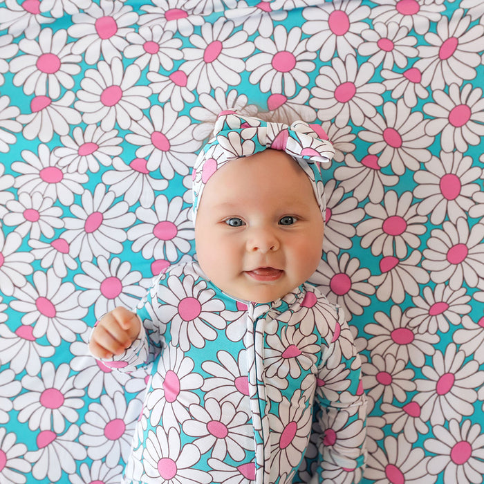 Baby in a floral outfit lying on a floral patterned blanket