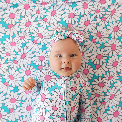 Baby in a floral outfit lying on a floral patterned blanket