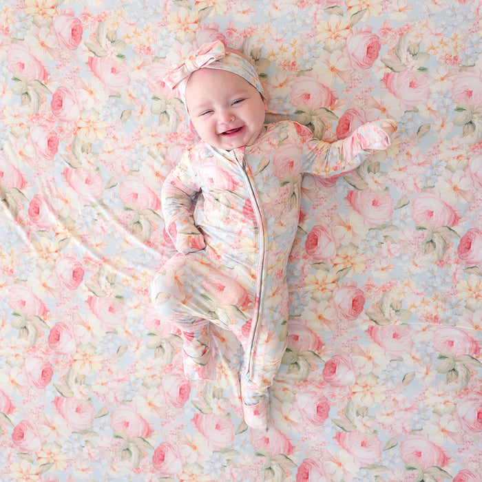 Baby in a floral outfit lying on a floral blanket