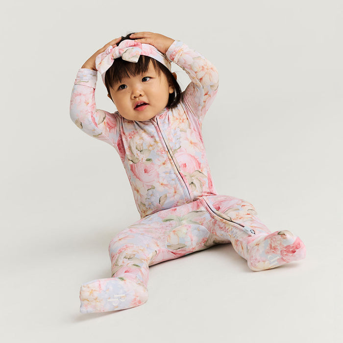 Child wearing a floral onesie on a plain background