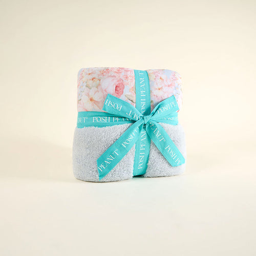 Folded blanket with floral pattern and turquoise ribbon on a light beige background