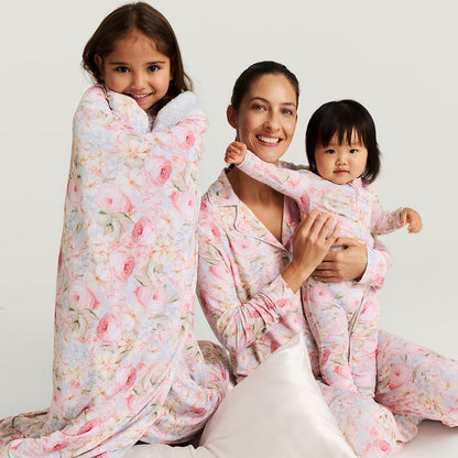 Woman and two children in matching floral pajamas on a white background