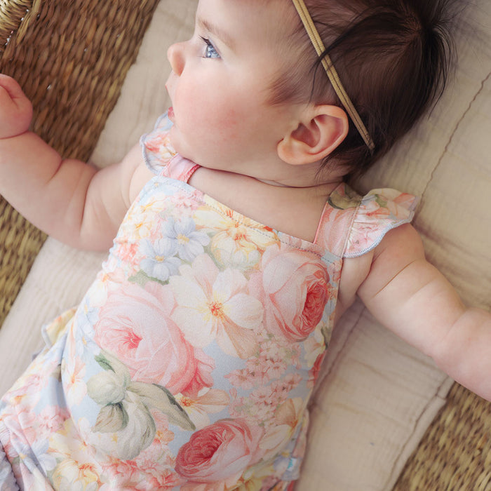 close up of baby wearing a floral romper in a wicker basket