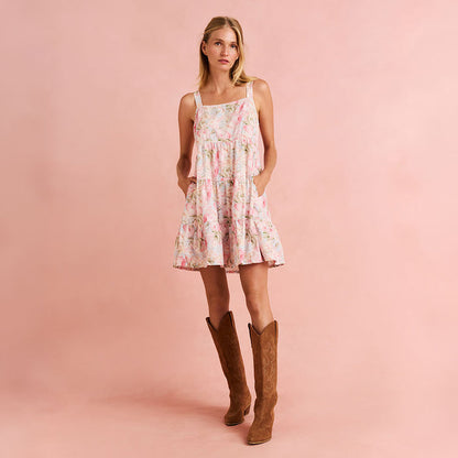Woman wearing a floral dress and brown boots on a pink background