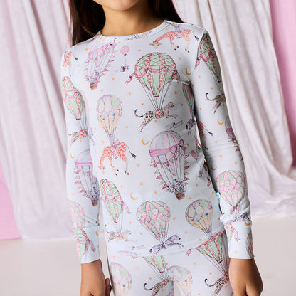 Person wearing a long-sleeve shirt with hot air balloon and animal pattern against a pink curtain background