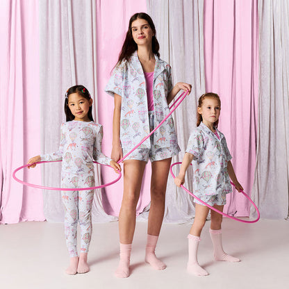 Woman and two children in matching pajama sets with pink hula hoops against a pink and gray curtain background.