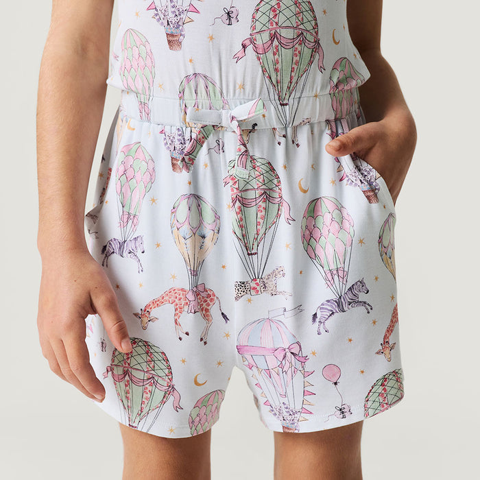 Child wearing a romper with hot air balloon and animal print on a plain background