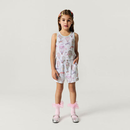Young girl wearing a patterned romper on a plain background