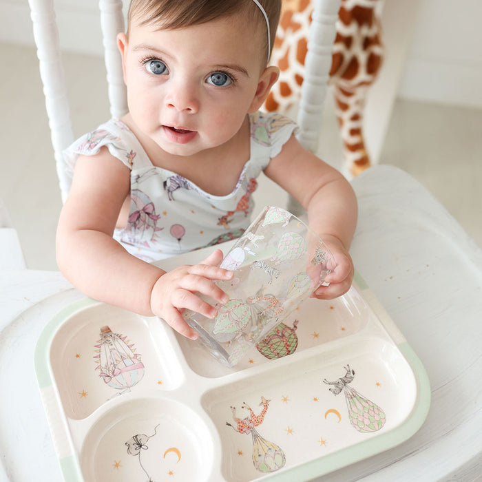Baby sitting in a high chair with a colorful plate and cup