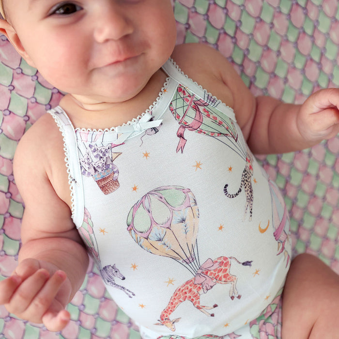 Baby wearing a colorful bodysuit with animal designs on a patterned background