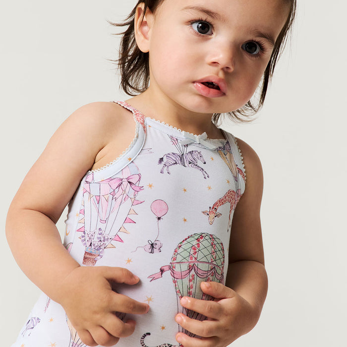 Child wearing a sleeveless bodysuit with animal and balloon designs on a plain background