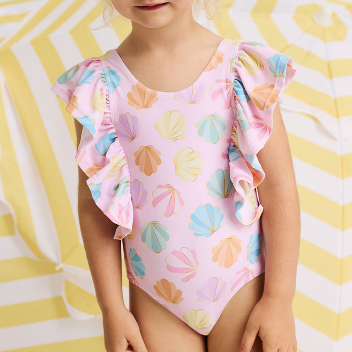 Child wearing a pink swimsuit with shell pattern on a yellow and white striped background