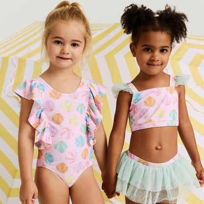 Two young girls wearing colorful swimsuits against a yellow and white striped background