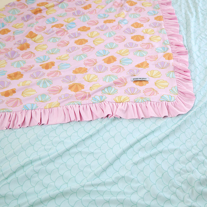 Pink blanket with shell pattern on a light blue reversible side.