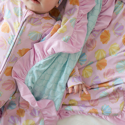 Close-up of a child wrapped in a colorful blanket with shell patterns