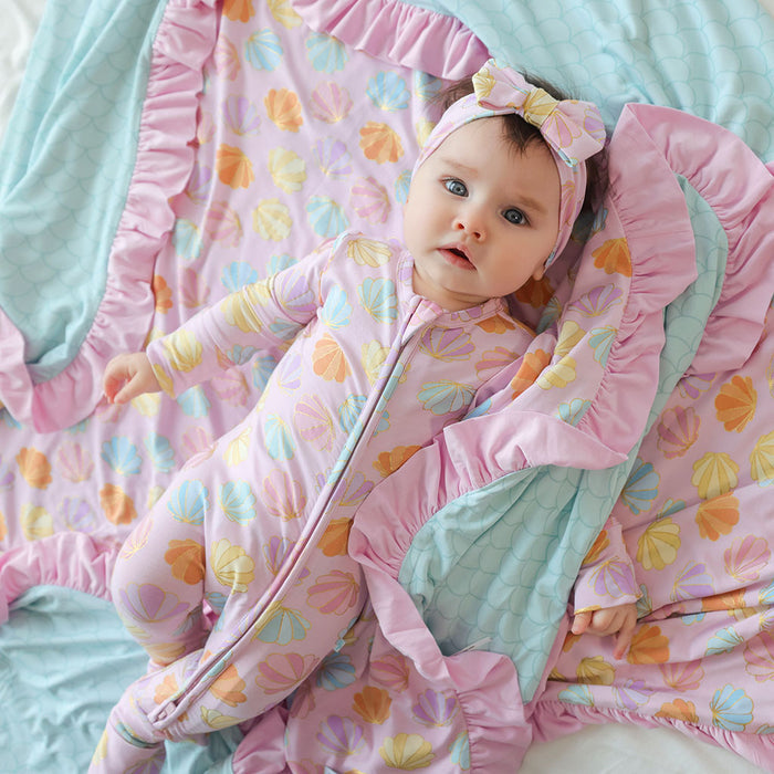 Baby wrapped in a colorful blanket with floral patterns on a light blue background